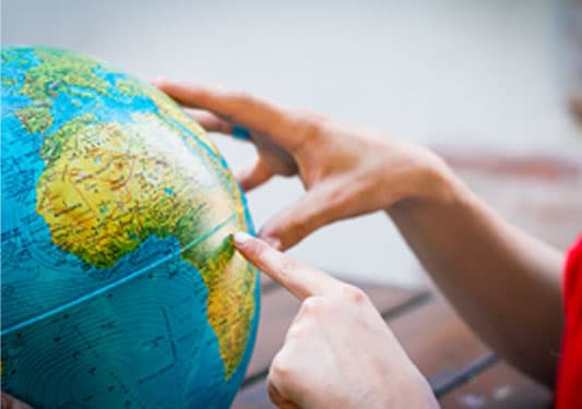 Person pointing at a globe.