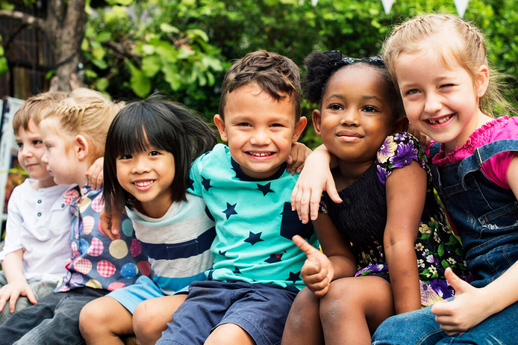 Group of kindergarten kids friends arm around sitting and smiling fun.